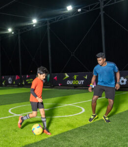 A closeup shot of a small boy and a trainer playing turf football in Chennai.