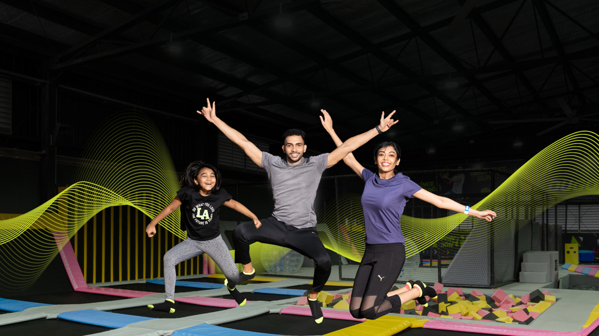 A happy family jumping in a trampoline arena at a trampoline park for adults in Chennai.